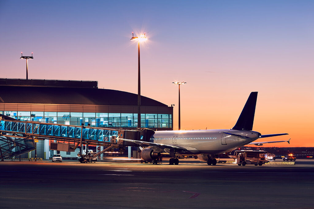 A plane coming in to dock at the terminal at dusk.