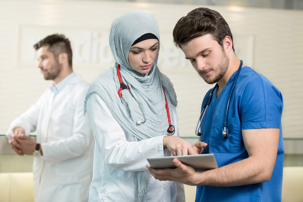 Doctors reviewing information on a tablet while at work.