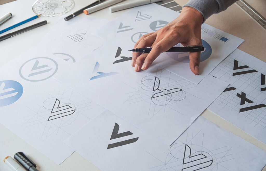 Logo Design variations shown on a large piece of paper.
