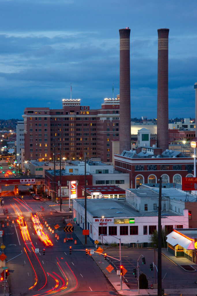 Downtown spokane at dusk with the smoke stacks framed in the righthand corner.