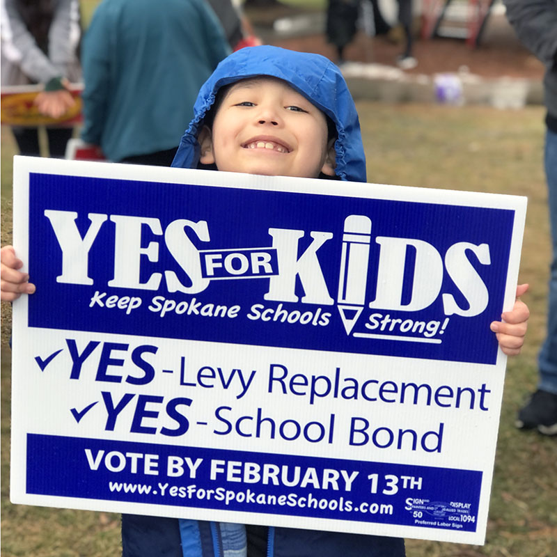 Kid holding Yes for Kids sign